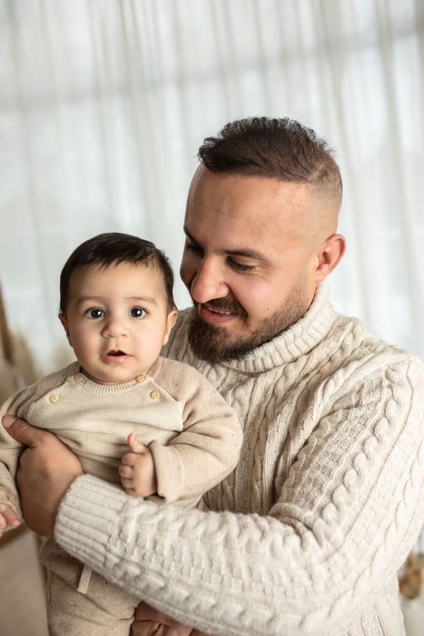 Papa im Strickpullover hält seinen kleinen Sohn im Arm