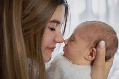 Neugeborenes schlafend auf dem Bauch der Mutter