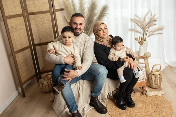 Familie mit zwei kleinen Söhnen sitzt auf einer Bank im hellen Atelier zwischen Pampasgras
